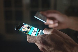 A man holding his mobile on one hand and a credit card in the other. The mobile screen has the words 'bet' on it.