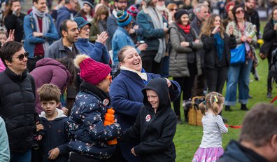Photograph of a crowd with two women and a boy laughing in the foreground