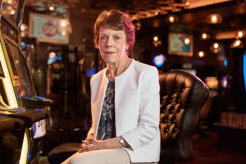 An elderly woman sitting in front of a pokies machine